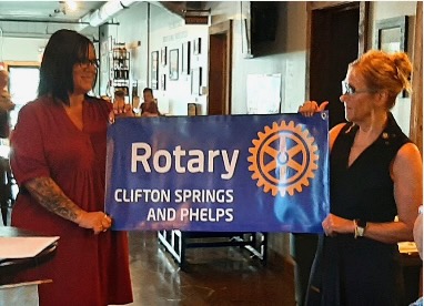 Two women holding the Clifton Springs and Phelps Rotary Club banner